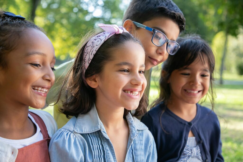 Happy children smiling together outdoors on a sunny day.